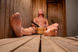 © Alexander - Stockholm, Sweden A naked man in sauna applies water to the heater with a scoop to create steam.