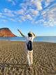 © neirfy - Exploring expansive sandy shoreline. Traveler in white navigates vast coast. Someone dressed in white with cap explores broad shoreline showcasing freedom and discovery