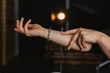 © Olga - Close up of a woman showing her elegant silver link bracelet on her wrist in a studio setting.