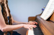 © Slizo - Person Playing Piano While Reading Sheet Music on an Acoustic Upright Piano