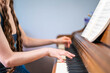 © Slizo - Person Playing Piano While Reading Sheet Music on an Acoustic Upright Piano