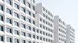 © rasdiana - Low angle view of a modern skyscraper building with a white geometric triangular pattern facade against a clear sky.