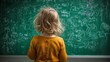© Nazia - Back view of unrecognizable adorable child drawing on green classroom board during school lesson