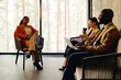 © Westend61 - Businesswoman discussing with colleagues sitting by glass window at convention center