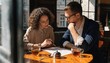 © Kayden - Two focused colleagues review a printed proposal over amber tea at a sunny cafe table, sharing strategy, careful notes and warm window light in a photorealistic business meeting scene