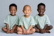 © Iryna - Three smiling toddlers sitting crosslegged in mint shirts on a gray background for family banner and children portrait background