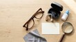 © Konstantin - Flat lay of healthcare and sensory assistance items on wooden table. Eyeglasses hearing aid magnifying glass and eye drops. Blank card with copy space for text