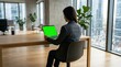 © Sumaiya - Professional woman working on a laptop with green screen in modern office