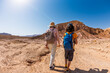 © zhukovvvlad - Two active backpackers stroll through the desert against a blue sky. Mother and child on a hike. Summer camp. Timna National Park. The child is actively spending time.