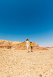 © zhukovvvlad - A boy with a backpack and a map walks next to his mother through the desert. Family trekking. Timna National Park. The child is actively spending time.