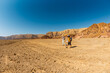 © zhukovvvlad - Two active backpackers stroll through the desert against a blue sky. Mother and child on a hike. Summer camp. Timna National Park. The child is actively spending time.