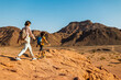 © zhukovvvlad - Two active backpackers stroll through the desert against a blue sky. Mother and child on a hike. Summer camp. Timna National Park. The child is actively spending time.