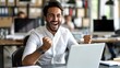 © Vlad Darii - Joyful office worker celebrating achievement on laptop, raising hands in excitement over good news