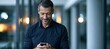 © Аrtranq - Smiling businessman using smartphone in modern office corridor