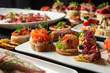 © pavel siamionov - A selection of gourmet catering appetizers and canapes with salmon, shrimp, prosciutto, and caviar on white plates, perfect for a party buffet or holiday celebration.