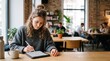 © Felippe Lopes - Young woman working on a tablet with a stylus in a modern cafe with blurred background patrons
