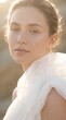 © Cielo Stray - A serene portrait of a young woman with natural skin and freckles dressed in ethereal white tulle fabric under a soft warm glow of golden hour sunlight