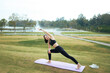 © PaeGAG - Young woman practicing yoga pose outdoors park