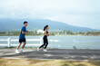 © PaeGAG - Young asian couple running together outdoors along lake