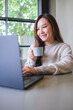 © Farknot Architect - Vertical portrait image of a woman drinking coffee while working on laptop computer