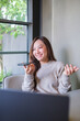 © Farknot Architect - Vertical of a woman holding smart phone and using voice messaging, talking with ai assistant for Artificial intelligence concept while working on laptop