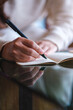 © Farknot Architect - Vertical closeup image of a woman writing on a notebook on the table