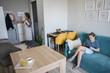 © artmim - Cute child girl using a tablet gadget while her mother does housework at home