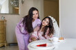 © millaf (Nemchinova) - Smiling little girl in pink pajamas with her mom eating in kitchen