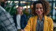 © Maksym - Young professional freezing mid-handshake after a colleague makes an offhanded comment about her accent in front of clients, microaggression moment, office setting, workplace belonging, cultural ins