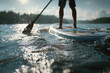 © Евгения Гаращенко - Person standing on a stand-up paddleboard viewed from the back during a peaceful summer adventure