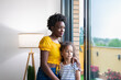 © ADDICTIVE STOCK - Mother and daughter standing by window at home, bonding