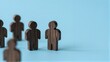© YiuCheung - Wooden figures stand in a row against a soft blue background, symbolizing unity or teamwork.