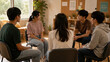 © Teeradej - Small group of Asian teenagers sitting in a circle in a bright community room, relaxed open postures, sense of mutual support and safe space.