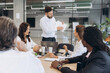 © anatoliycherkas - Businessman presenting financial data while multinational colleagues discuss marketing strategy in a modern office