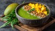© Captain - A green smoothie bowl topped with fresh mango chunks crunchy granola coconut flakes and mint leaves in a coconut shell