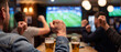 © itlada - Sports fans cheering in a bar with raised fists while watching a football match on a large screen, featuring beer glasses on a wooden table in a warm atmospheric pub setting
