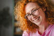 © Miljan Živković - Happy red-haired young woman smiling with freckles wearing glasses