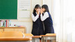 © キャラメルhanabi - ひそひそ話（内緒の話）をしている女子生徒たち２人のイメージ　日本人の学校生活