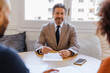 © BONNINSTUDIO/Stocksy - Financial advisor smiling during consultation meeting with clients