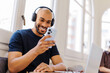 © BONNINSTUDIO/Stocksy - Smiling man in headphones using phone at bright workspace