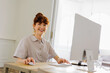 © BONNINSTUDIO/Stocksy - Professional woman smiling while working on computer at bright office