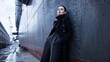 © NIMAS - High Fashion Woman in Elegant Black Coat Posing Against Industrial Steel Ship Hull at Dock