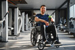 © Serhii - Man with disability smiling and holding a drink in a wheelchair at the gym