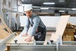 © Serhii - Carpenter working with wood panel on cnc machine in furniture factory
