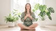 © Hypnyo - Young woman meditating with hands on heart in bright indoor garden surrounded by green houseplants for wellness and mindfulness content