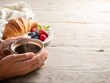 © Serjio - Momento de desayuno con café y croissant en una mesa de madera