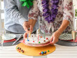© luciano - Senior couple celebrating a seventy-fifth birthday, the man lighting candles on a homemade cake while his partner holds the plate, creating a warm and festive atmosphere