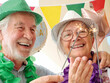 © luciano - Senior couple joyfully celebrating birthday party with sparklers, wearing festive hats and leis, expressing happiness and togetherness during special event