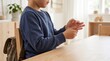 © Olivia - Young boy sitting at desk at home holding his painful hurting hand