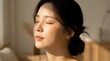 © Undersea - Young East Asian woman with eyes closed in serene expression, experiencing relaxation, wellness, or skincare routine in warm indoor lighting.